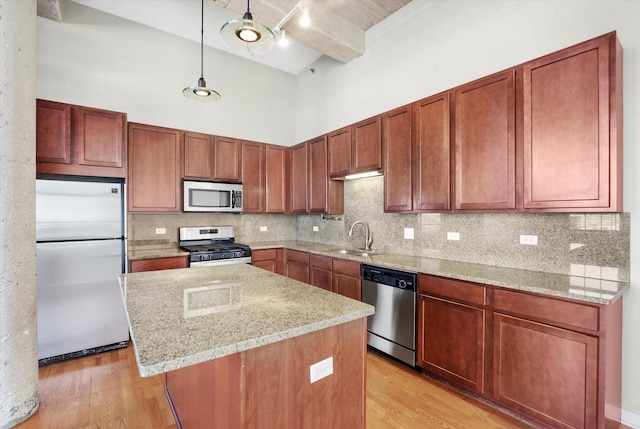 3963 W Belmont Ave Unit 613, Chicago, IL 60618 - kitchen featuring stainless steel appliances, a high ceiling, light wood finished floors, a kitchen island, and decorative backsplash