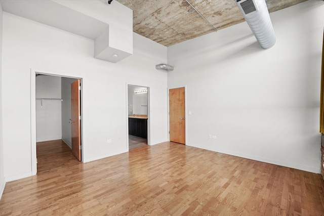 3963 W Belmont Ave Unit 613, Chicago, IL 60618 - unfurnished bedroom with light wood finished floors, a spacious closet, a closet, and connected bathroom