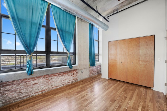 3963 W Belmont Ave Unit 613, Chicago, IL 60618 - unfurnished bedroom with brick wall, wood finished floors, a high ceiling, a closet, and multiple windows