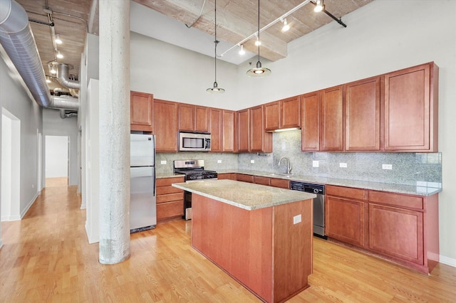 3963 W Belmont Ave Unit 613, Chicago, IL 60618 - kitchen featuring stainless steel appliances, a high ceiling, track lighting, light wood finished floors, and a kitchen island