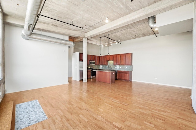 3963 W Belmont Ave Unit 613, Chicago, IL 60618 - kitchen featuring appliances with stainless steel finishes, open floor plan, a towering ceiling, decorative backsplash, and a center island