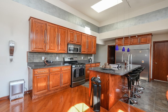 2069 Willow Brook Dr, Bourbonnais, IL 60914 - kitchen with appliances with stainless steel finishes, brown cabinetry, a breakfast bar, backsplash, and a towering ceiling