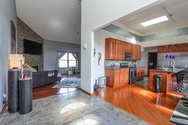2069 Willow Brook Dr, Bourbonnais, IL 60914 - kitchen with stainless steel appliances, high vaulted ceiling, open floor plan, dark countertops, and a fireplace