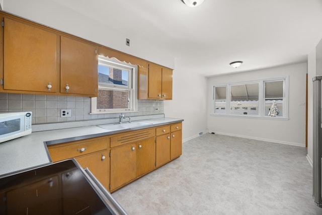 4316 N Sayre Ave, Norridge, IL 60706 - kitchen with light flooring, white microwave, light countertops, tasteful backsplash, and brown cabinets