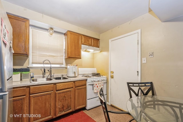 13937 S School St, Riverdale, IL 60827 - kitchen featuring gas range gas stove, under cabinet range hood, light countertops, brown cabinets, and freestanding refrigerator