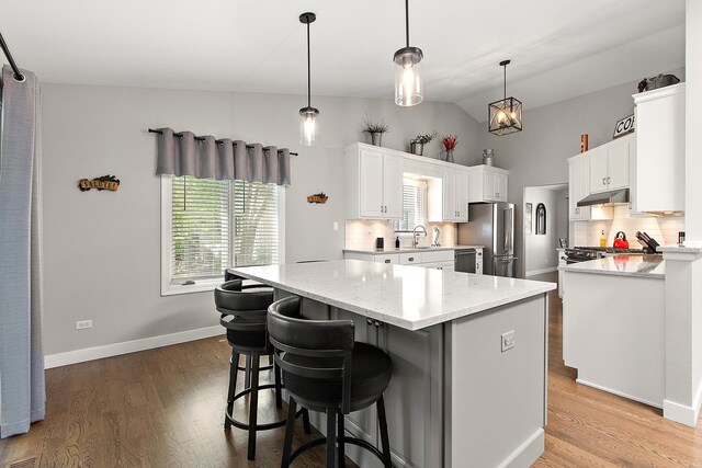 16243 Hummingbird Hill Dr, Orland Park, IL 60467 - kitchen with appliances with stainless steel finishes, a center island, decorative backsplash, vaulted ceiling, and white cabinetry