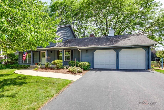 400 Seafarer Dr, Third Lake, IL 60030 - view of front facade with an attached garage, a chimney, asphalt driveway, a front lawn, and board and batten siding