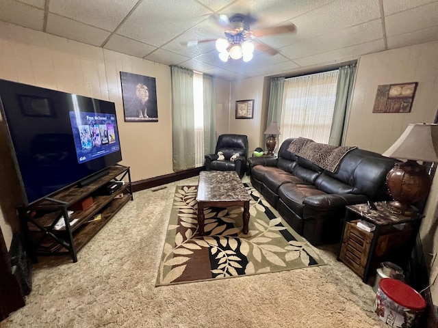 205 E St, Penfield, IL 61862 - carpeted living area featuring a paneled ceiling, a ceiling fan, and wooden walls