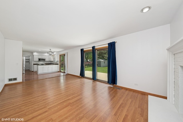600 N Brookdale Dr, Schaumburg, IL 60194 - unfurnished living room with light wood-type flooring, a chandelier, recessed lighting, and a brick fireplace