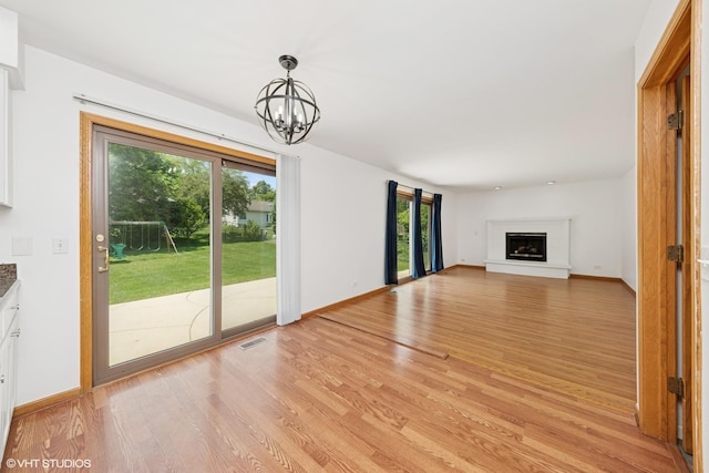 600 N Brookdale Dr, Schaumburg, IL 60194 - unfurnished living room with light wood finished floors, a chandelier, and a fireplace with raised hearth