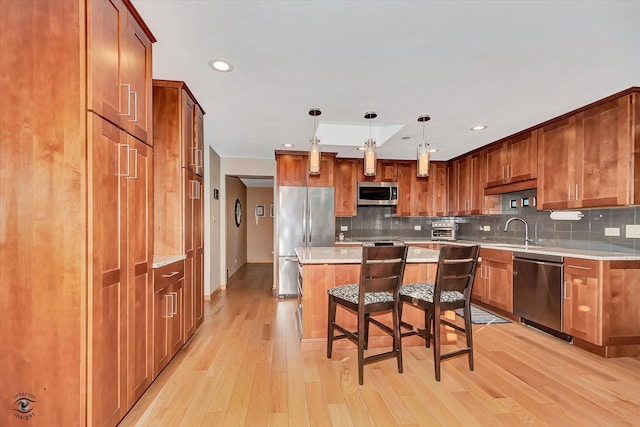 13348 S Stephen Dr, Palos Park, IL 60464 - kitchen featuring appliances with stainless steel finishes, light wood-style flooring, a kitchen island, a kitchen bar, and tasteful backsplash