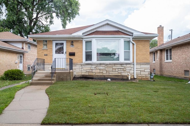 bungalow-style house featuring a front lawn, stone siding, and brick siding