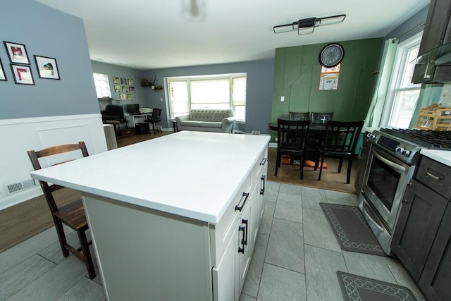 kitchen featuring stainless steel range with gas stovetop, a breakfast bar, a kitchen island, light countertops, and open floor plan