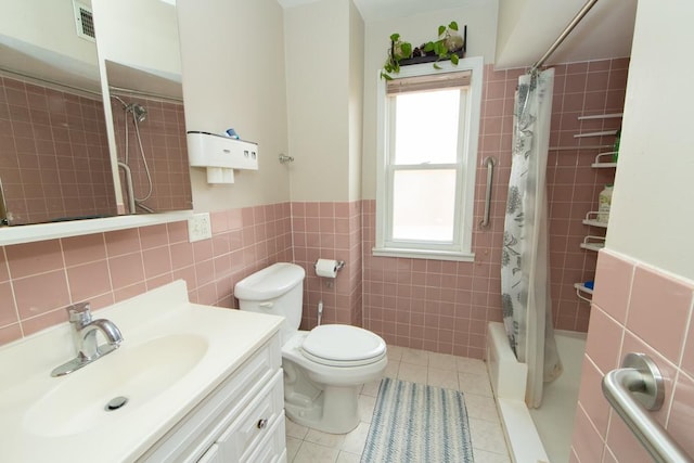 bathroom with tile walls, vanity, shower / bath combination with curtain, tile patterned flooring, and wainscoting
