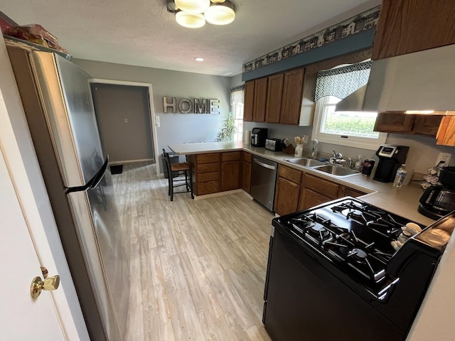 18367 US-150 Hwy, Bloomington, IL 61705 - kitchen with stainless steel appliances, a peninsula, light wood-style flooring, light countertops, and brown cabinets