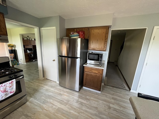 18367 US-150 Hwy, Bloomington, IL 61705 - kitchen with appliances with stainless steel finishes, light wood-style floors, light countertops, brown cabinets, and a textured ceiling