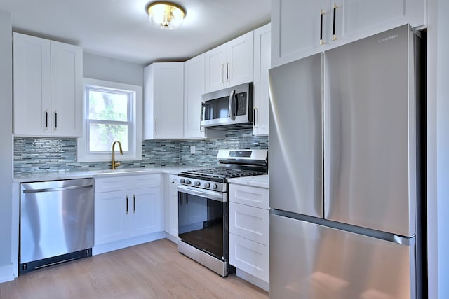 2024 S 24th Ave, Broadview, IL 60155 - kitchen featuring appliances with stainless steel finishes, light countertops, tasteful backsplash, light wood finished floors, and white cabinetry