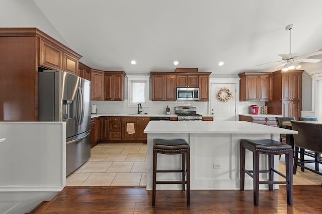14301 S California Ave, Posen, IL 60469 - kitchen featuring stainless steel appliances, decorative backsplash, light countertops, a breakfast bar, and ceiling fan