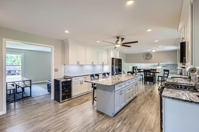 1718 Rosewood Ln, Johnsburg, IL 60051 - kitchen featuring ceiling fan, wine cooler, gas stove, a breakfast bar, and decorative backsplash