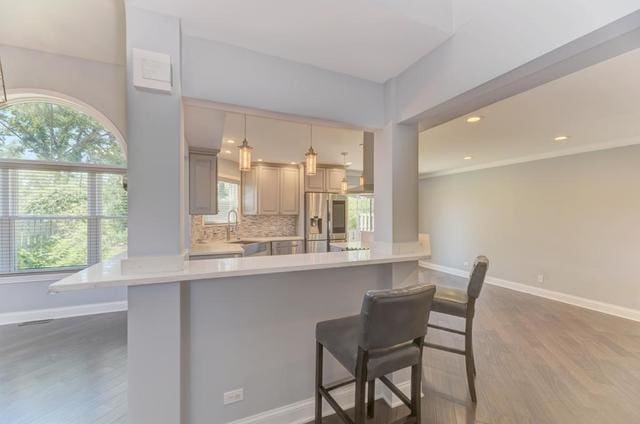 2716 Burton Dr, Westchester, IL 60154 - kitchen featuring stainless steel fridge with ice dispenser, a breakfast bar, light countertops, wood finished floors, and wall chimney exhaust hood