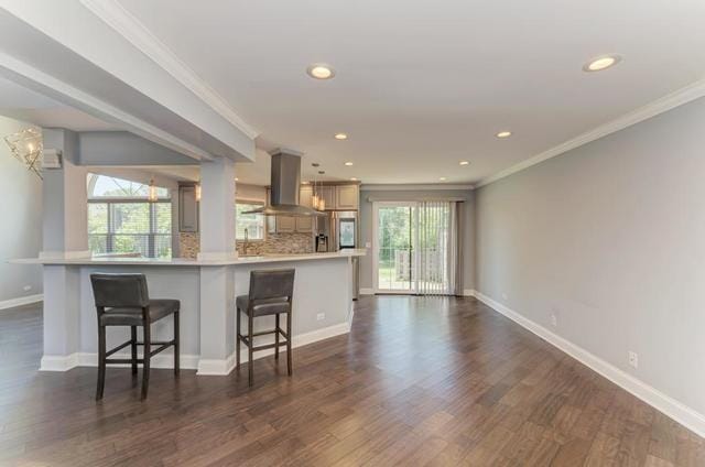 2716 Burton Dr, Westchester, IL 60154 - kitchen with wall chimney range hood, a breakfast bar, ornamental molding, light countertops, and dark wood finished floors
