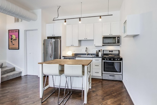 1720 N Marshfield Ave Unit 108, Chicago, IL 60622 - kitchen featuring appliances with stainless steel finishes, butcher block countertops, a kitchen bar, backsplash, and dark wood finished floors
