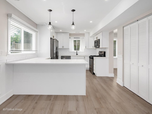 865 W Bryn Mawr Ave, Roselle, IL 60172 - kitchen featuring appliances with stainless steel finishes, a peninsula, tasteful backsplash, light wood-type flooring, and white cabinets