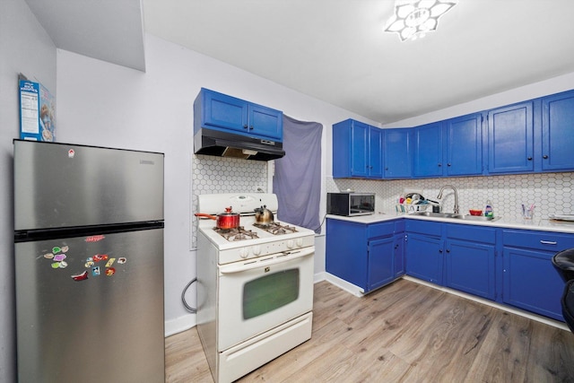 4532 S Laflin St, Chicago, IL 60609 - kitchen featuring freestanding refrigerator, gas range gas stove, under cabinet range hood, blue cabinetry, and light wood finished floors