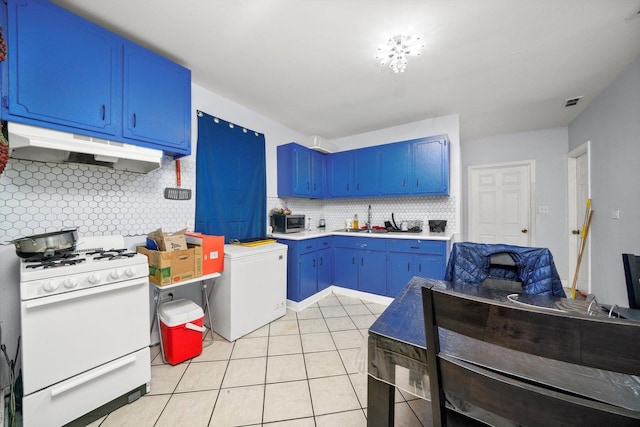 4532 S Laflin St, Chicago, IL 60609 - kitchen featuring white gas stove, under cabinet range hood, blue cabinetry, stainless steel microwave, and tasteful backsplash