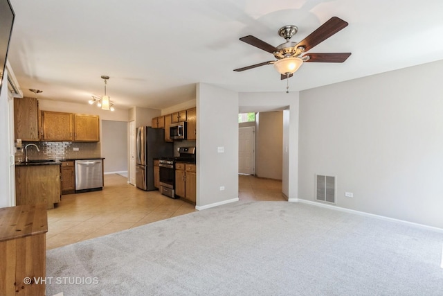 1109 Blackburn Dr, Grayslake, IL 60030 - kitchen featuring stainless steel appliances, dark countertops, brown cabinetry, light carpet, and decorative backsplash
