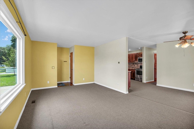 203 E Wilson, Tuscola, IL 61953 - unfurnished living room featuring healthy amount of natural light, dark colored carpet, and a ceiling fan