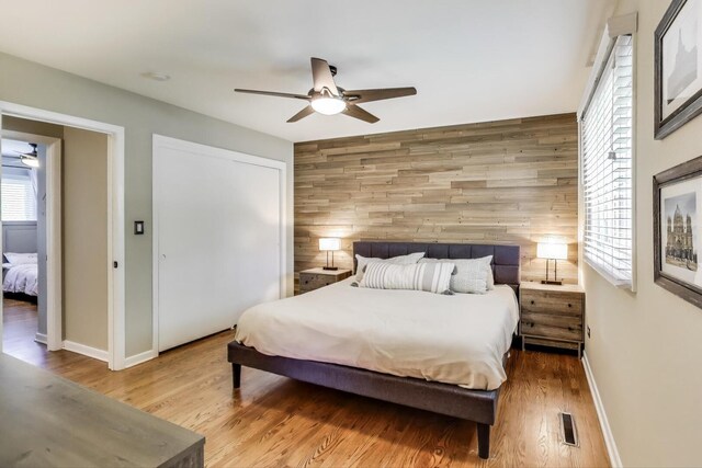 141 S Cedar St, Palatine, IL 60067 - bedroom featuring wooden walls, wood finished floors, ceiling fan, a closet, and an accent wall