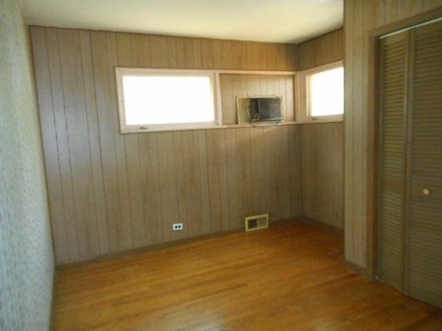 219 N Wilke Rd, Arlington Heights, IL 60005 - unfurnished bedroom featuring wood finished floors, a closet, and wooden walls