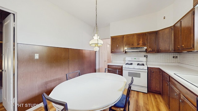 3120 N Natoma Ave, Chicago, IL 60634 - kitchen featuring white range with gas cooktop, under cabinet range hood, light wood-style floors, light countertops, and wainscoting