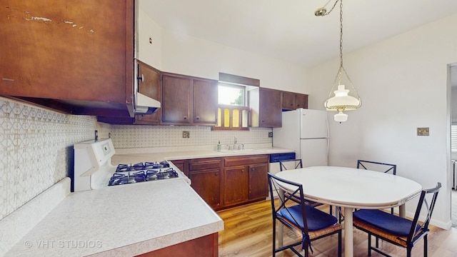 3120 N Natoma Ave, Chicago, IL 60634 - kitchen featuring white appliances, light countertops, light wood-style floors, under cabinet range hood, and decorative backsplash