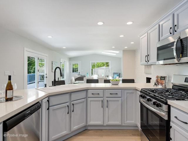 622 Pleasant Pl, Streamwood, IL 60107 - kitchen featuring appliances with stainless steel finishes, vaulted ceiling, light countertops, a peninsula, and recessed lighting