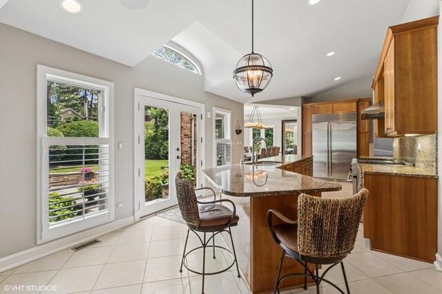 423 S Beverly Ln, Arlington Heights, IL 60005 - kitchen with stainless steel appliances, lofted ceiling, brown cabinetry, dark stone counters, and light tile patterned floors