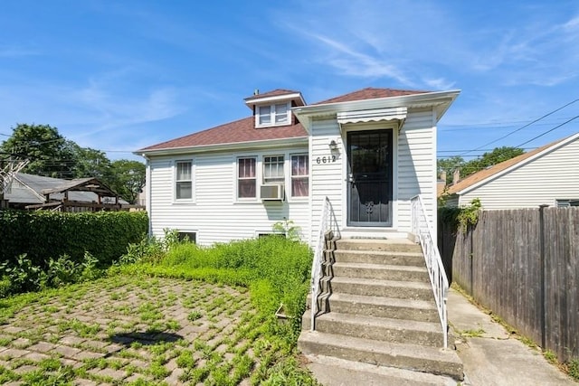 6612 N Mozart St, Chicago, IL 60645 - view of front facade featuring entry steps, cooling unit, and a shingled roof