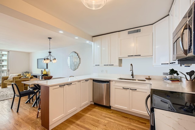 6007 N Sheridan Rd Unit 36F, Chicago, IL 60660 - kitchen with appliances with stainless steel finishes, a peninsula, light wood-type flooring, white cabinets, and recessed lighting