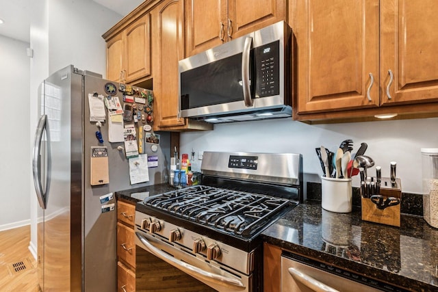 3041 N California Ave Unit 1, Chicago, IL 60618 - kitchen featuring stainless steel appliances, dark stone counters, brown cabinets, and light wood-type flooring