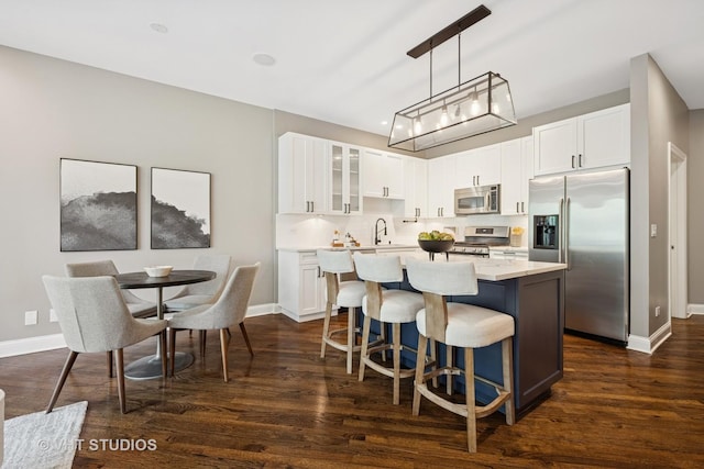 2259 W Wabansia Ave Unit 309, Chicago, IL 60647 - kitchen with stainless steel appliances, a kitchen island, dark wood-style flooring, glass insert cabinets, and light countertops