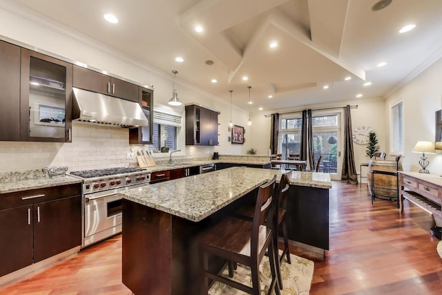 2011 W Huron St, Chicago, IL 60612 - kitchen with appliances with stainless steel finishes, under cabinet range hood, ornamental molding, a peninsula, and a breakfast bar area