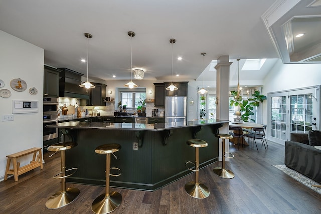 72 Gray St, Saint Charles, IL 60174 - kitchen with appliances with stainless steel finishes, wall chimney range hood, dark wood-style floors, tasteful backsplash, and a spacious island