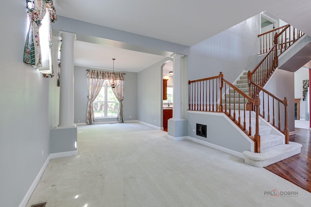 2208 Sanctuary Ct, Gurnee, IL 60031 - unfurnished living room with ornate columns, carpet, a chandelier, stairway, and arched walkways