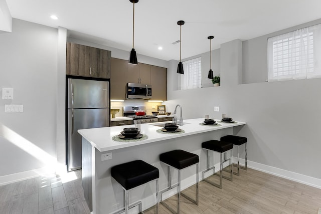 1538 W 21st St Unit 1, Chicago, IL 60608 - kitchen featuring appliances with stainless steel finishes, light wood finished floors, a peninsula, light countertops, and a kitchen bar