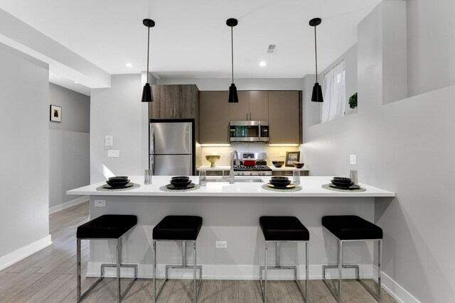 1538 W 21st St Unit 1, Chicago, IL 60608 - kitchen featuring stainless steel appliances, a kitchen bar, light countertops, backsplash, and light wood finished floors