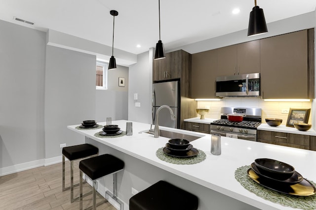 1538 W 21st St Unit 1, Chicago, IL 60608 - kitchen with stainless steel appliances, light countertops, light wood finished floors, a kitchen bar, and decorative backsplash