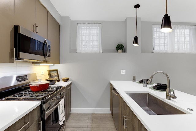 1538 W 21st St Unit 1, Chicago, IL 60608 - kitchen featuring appliances with stainless steel finishes, light countertops, decorative backsplash, pendant lighting, and light wood-type flooring