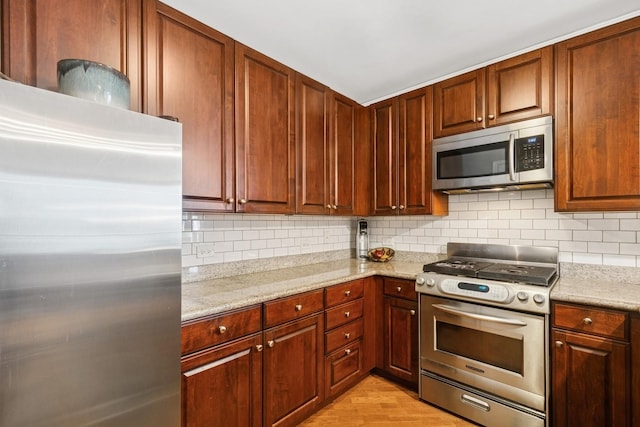 420 E Waterside Dr Unit 1302, Chicago, IL 60601 - kitchen featuring appliances with stainless steel finishes, tasteful backsplash, light wood-style floors, and light stone countertops