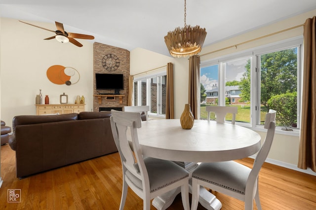 8909 Silverdale Dr Unit 5C, Orland Park, IL 60462 - dining area featuring a stone fireplace, plenty of natural light, light wood-style floors, lofted ceiling, and a chandelier